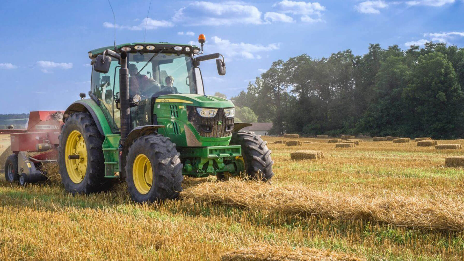 Green John Deer Tractor picking up hay to collect it into bales